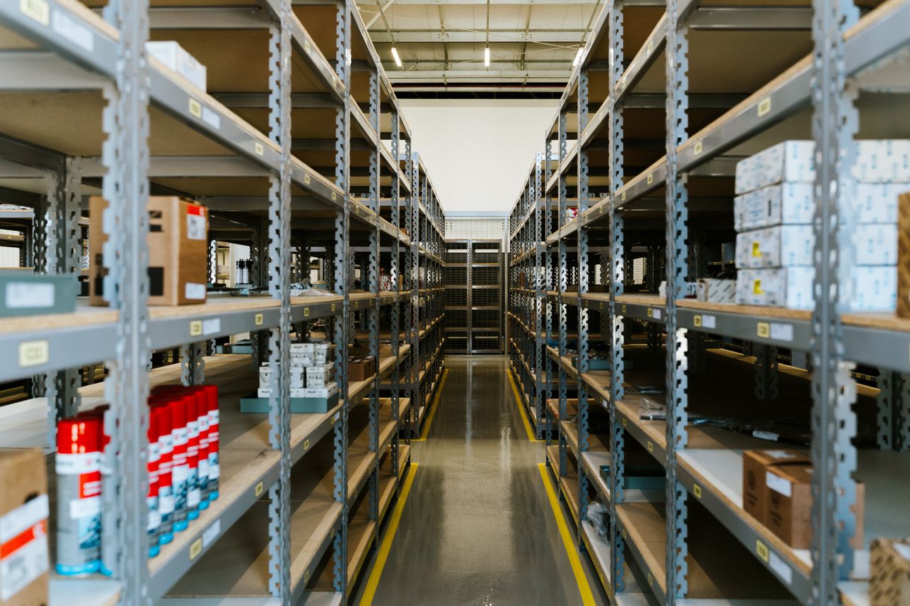 Wide view of an organized industrial warehouse with metal shelving and stored merchandise.