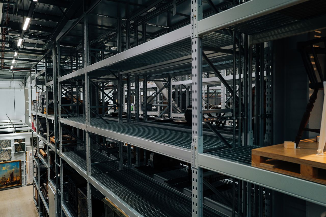 About Empty metal storage racks in a spacious industrial warehouse setting.